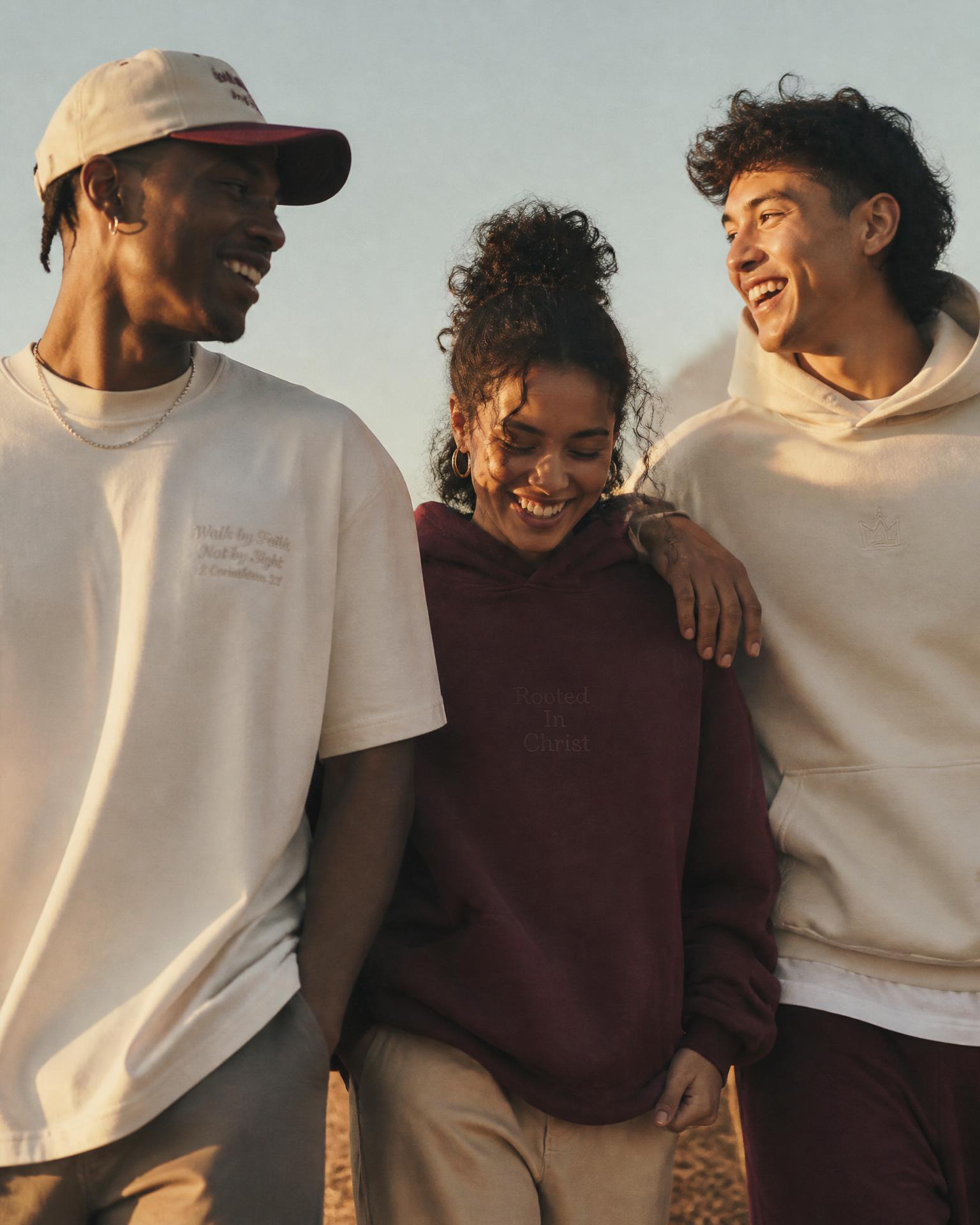 Friends wearing Faith Talk apparel laughing together in golden hour light